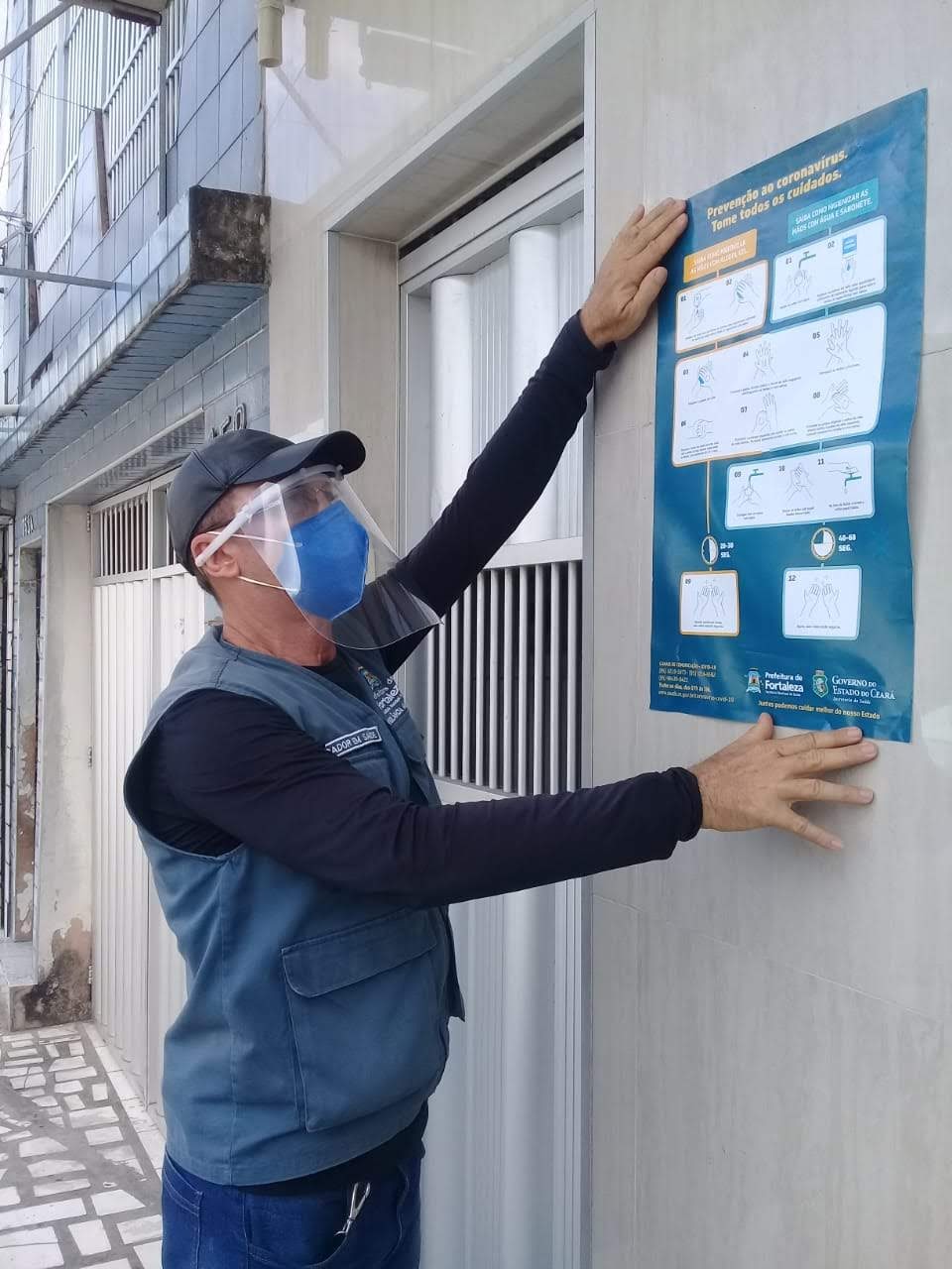 homem de máscara colando cartaz e parede